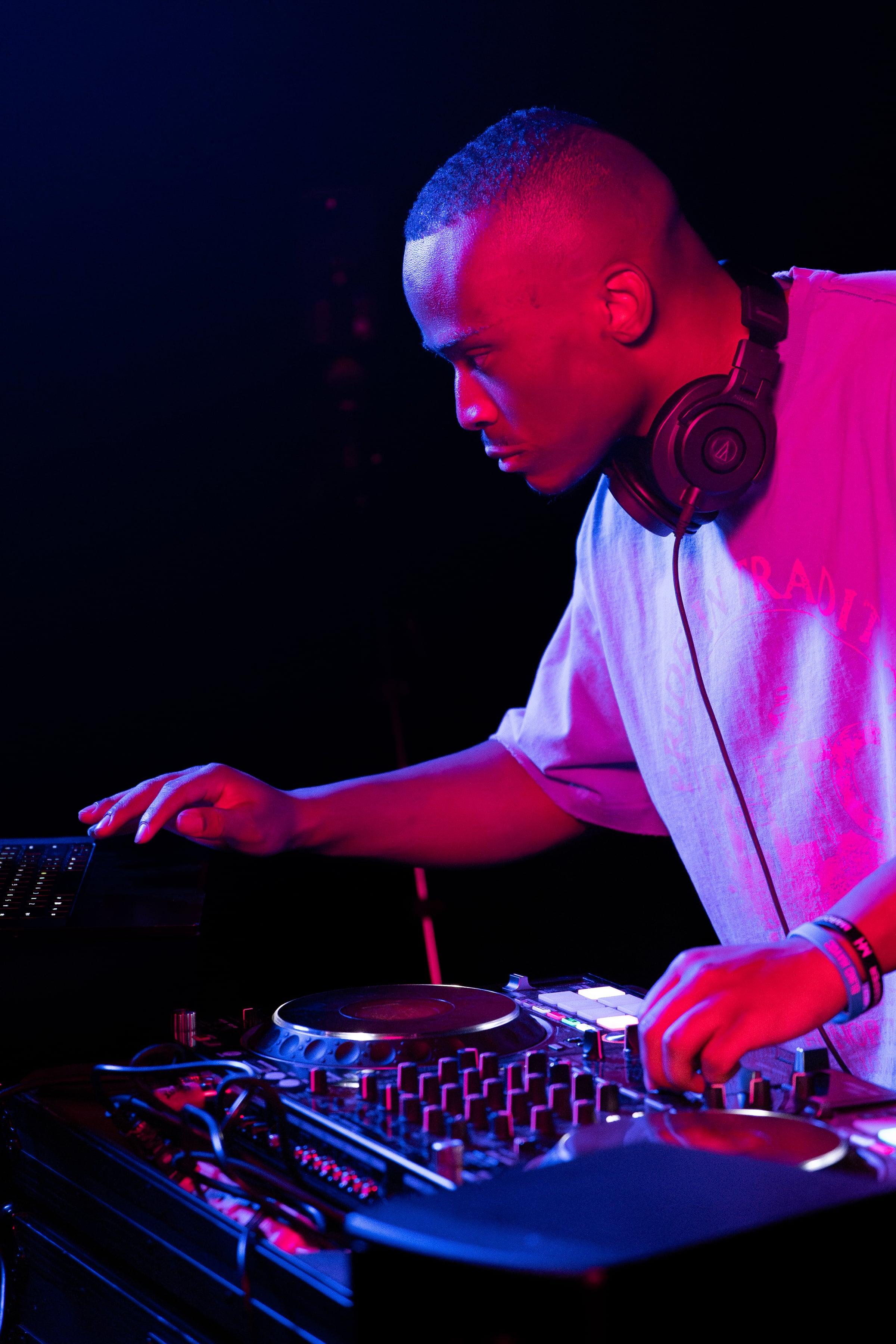 MH in profile leaning over the controller under magenta and blue light