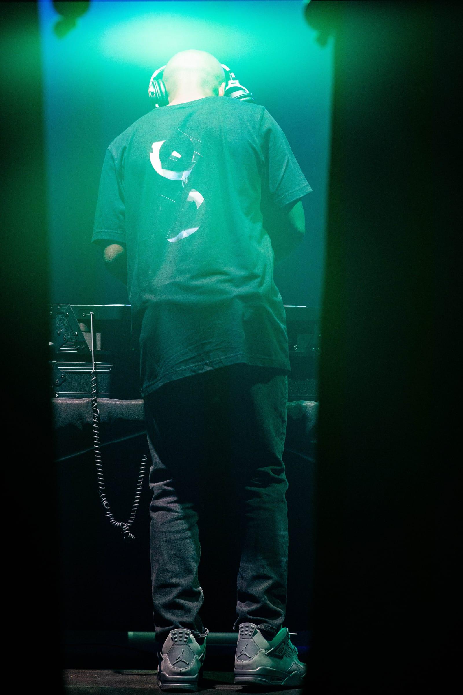 MH seen from behind at the decks in a green-lit doorway