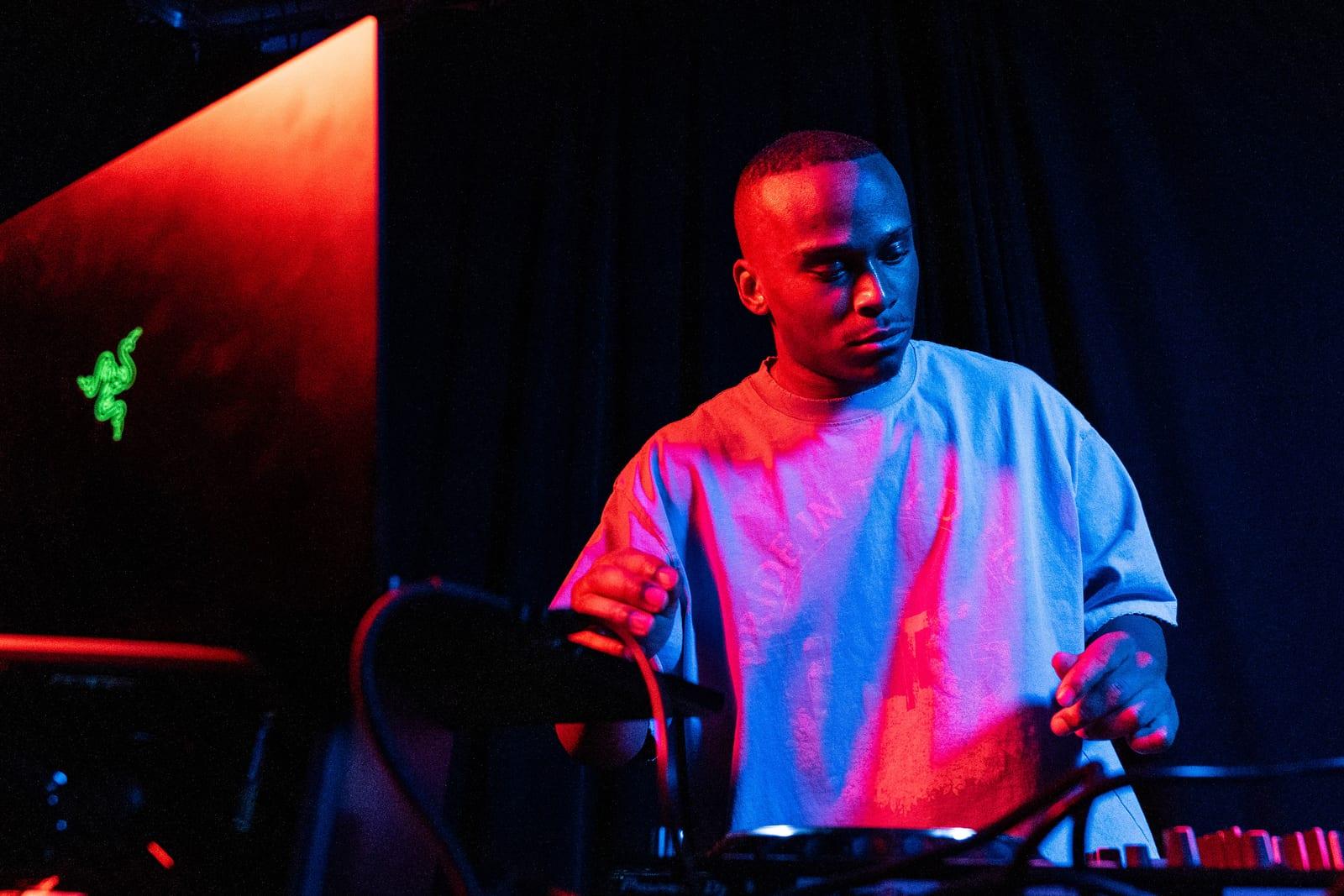 MH performing behind DJ gear under red and blue stage lighting